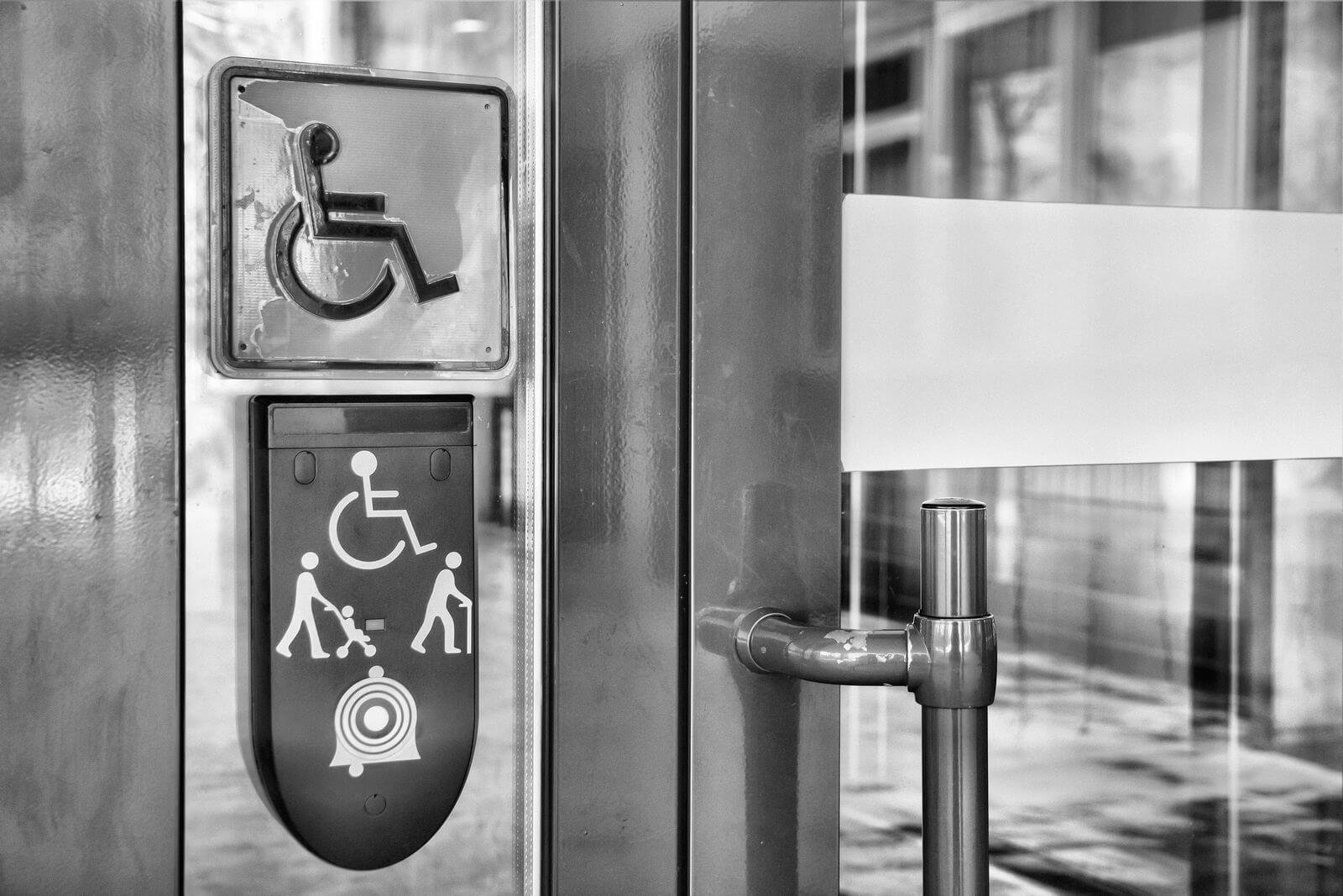 Call on glass front door of building and plaque with image of disabled person in wheelchair and people with walking stick